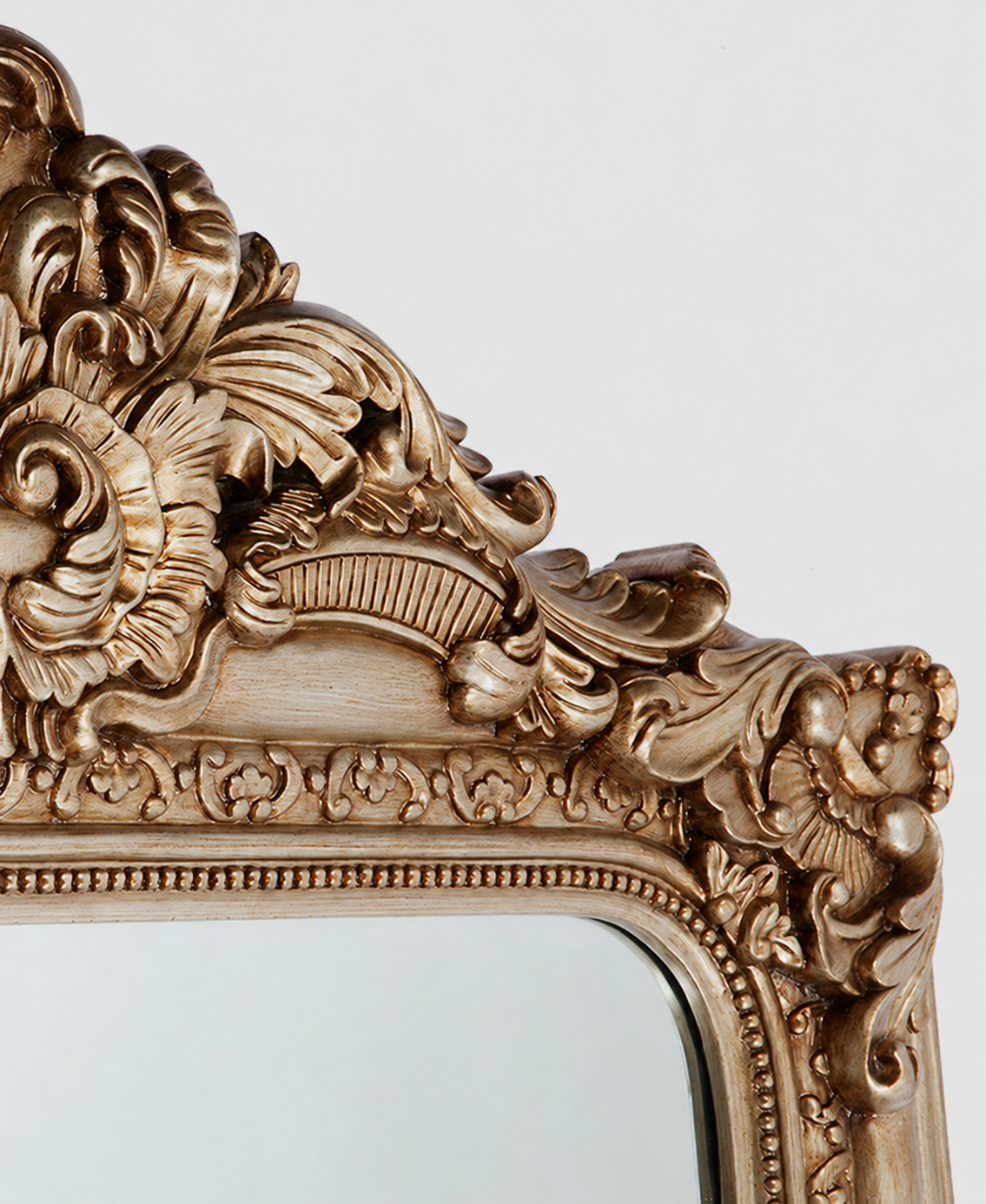 Close-up of the ornate carved gold frame on the French Baroque mirror