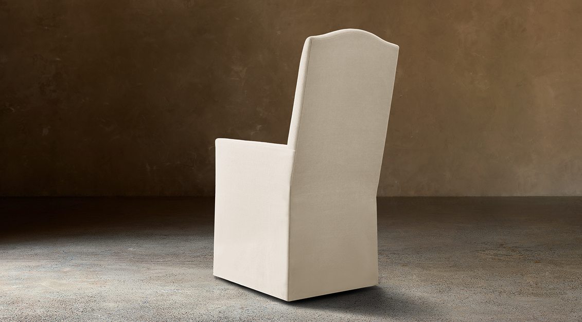 Alexandria Camelback Fabric Dining Armchair – rear three-quarter view in natural-toned upholstery