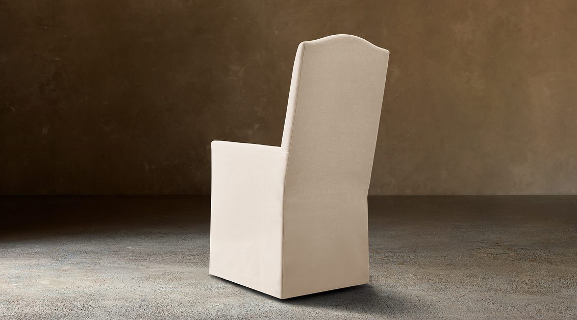 Alexandria Camelback Fabric Dining Armchair With Nailheads – rear three-quarter view in natural-toned upholstery