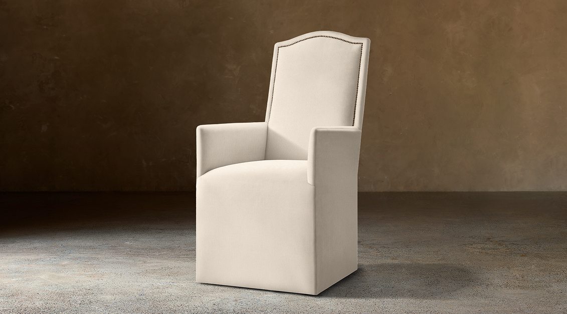 Alexandria Camelback Fabric Dining Armchair With Nailheads – three-quarter view in natural-toned upholstery